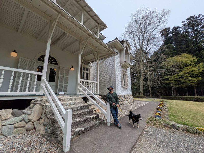 洋館の前に立つ犬と男性